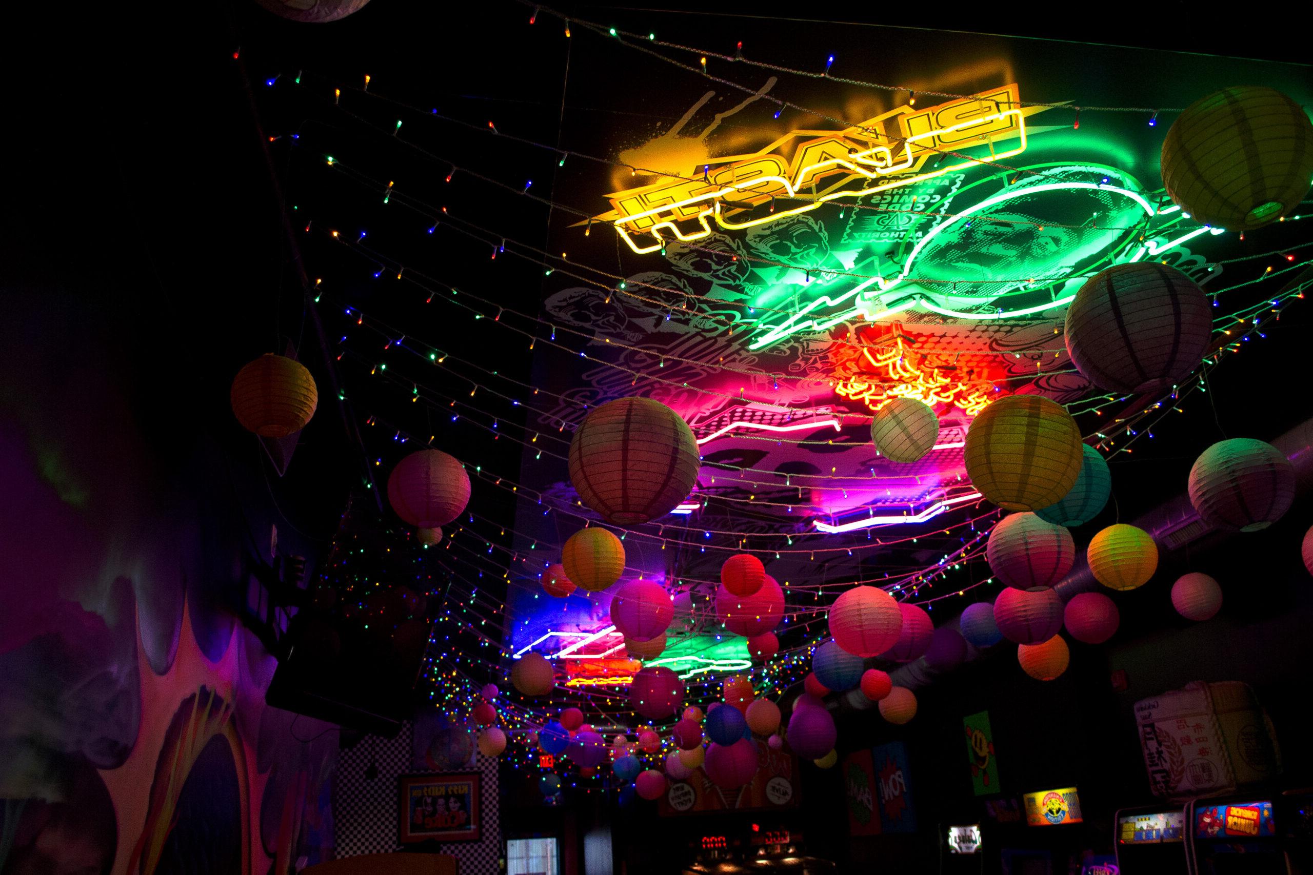 Photo of dark room with colorful lights and balloon lanterns hanging from ceiling